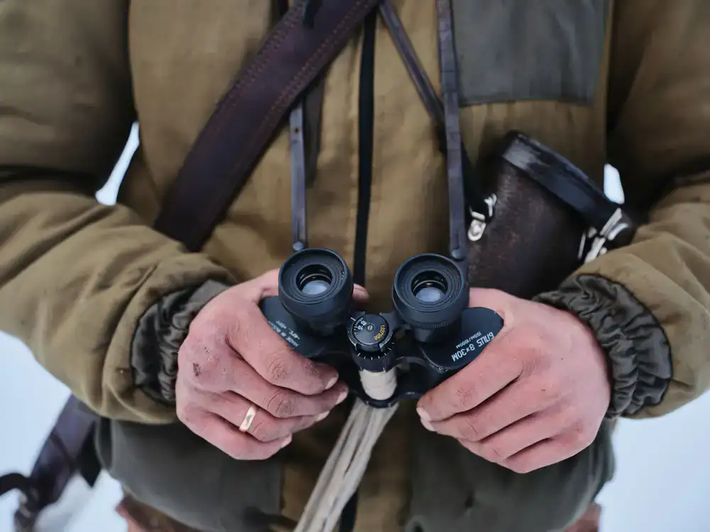 Close up of a naturalist holding binoculars in a misty wetland
